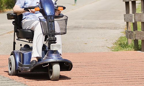 elderly woman driving power scooter down the road