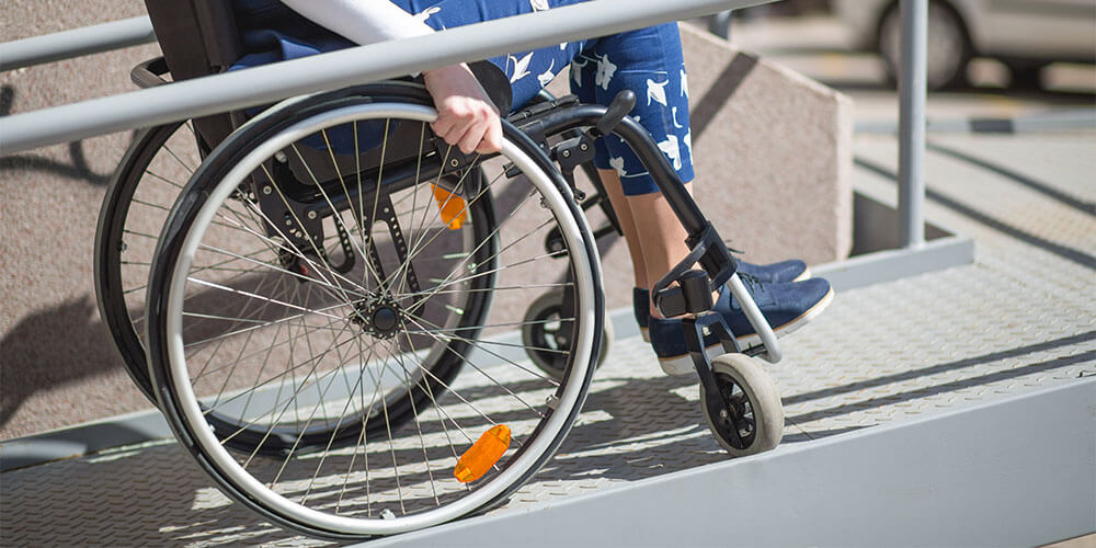 person in wheelchair going up ramp