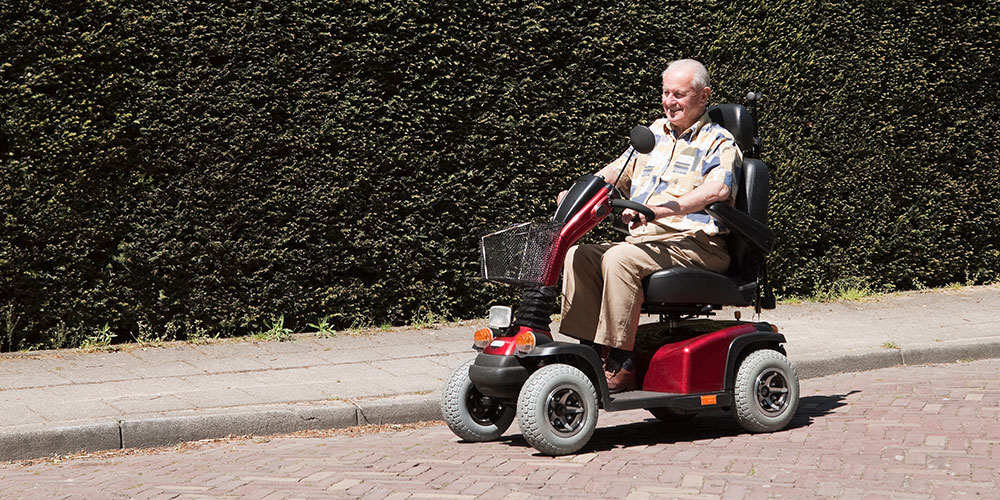 older man riding his power scooter on street